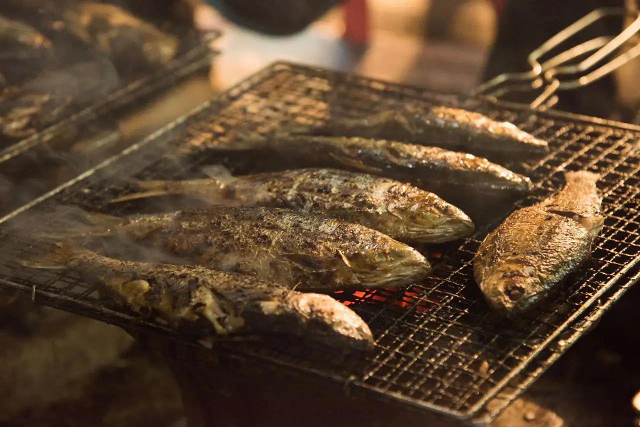 숯불 석쇠 위에 생선 여러 마리가 노릇하게 구워지고 있다