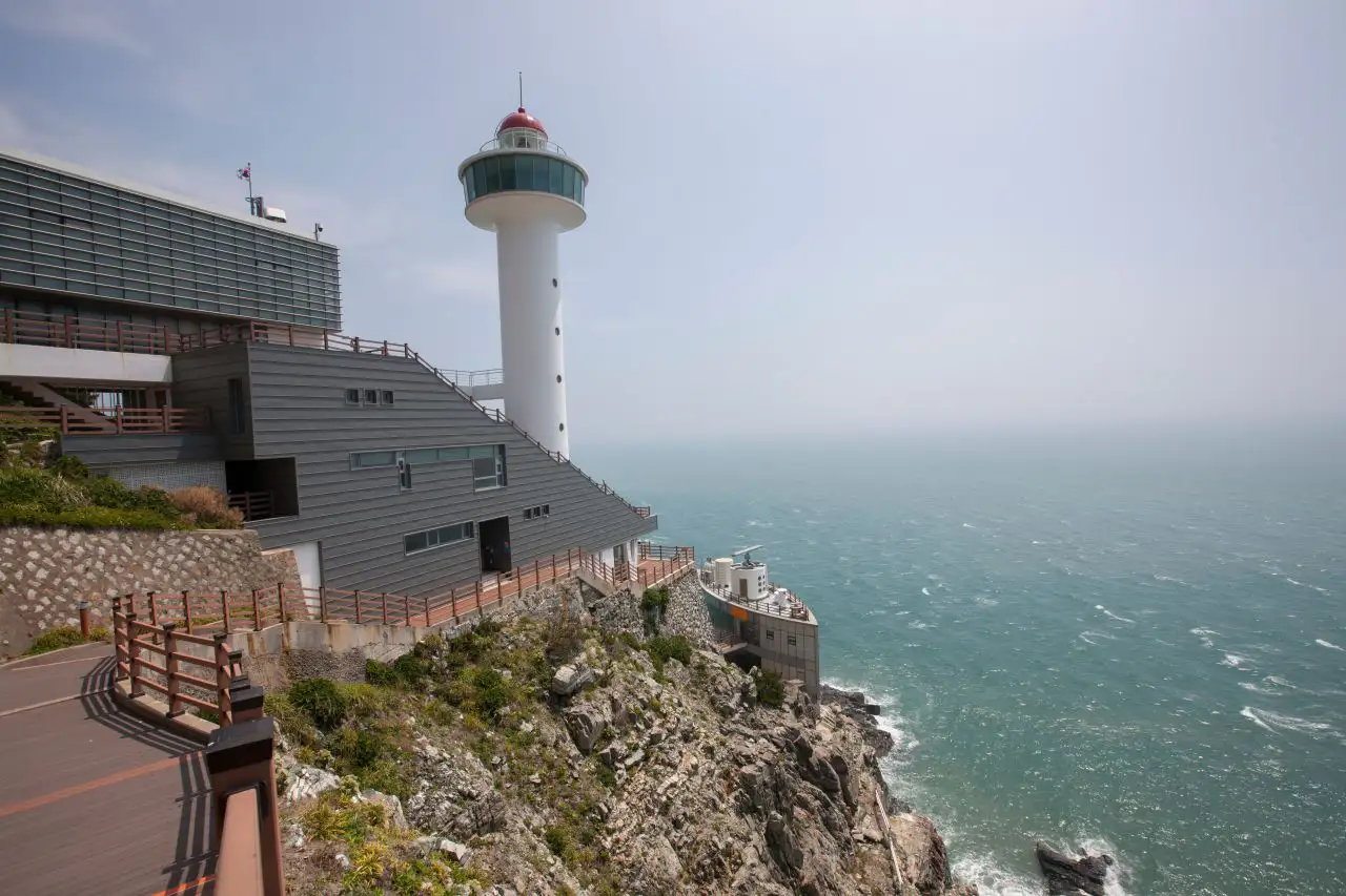 The white Yeongdo Lighthouse and its exhibition building on the cliff edge above the sea