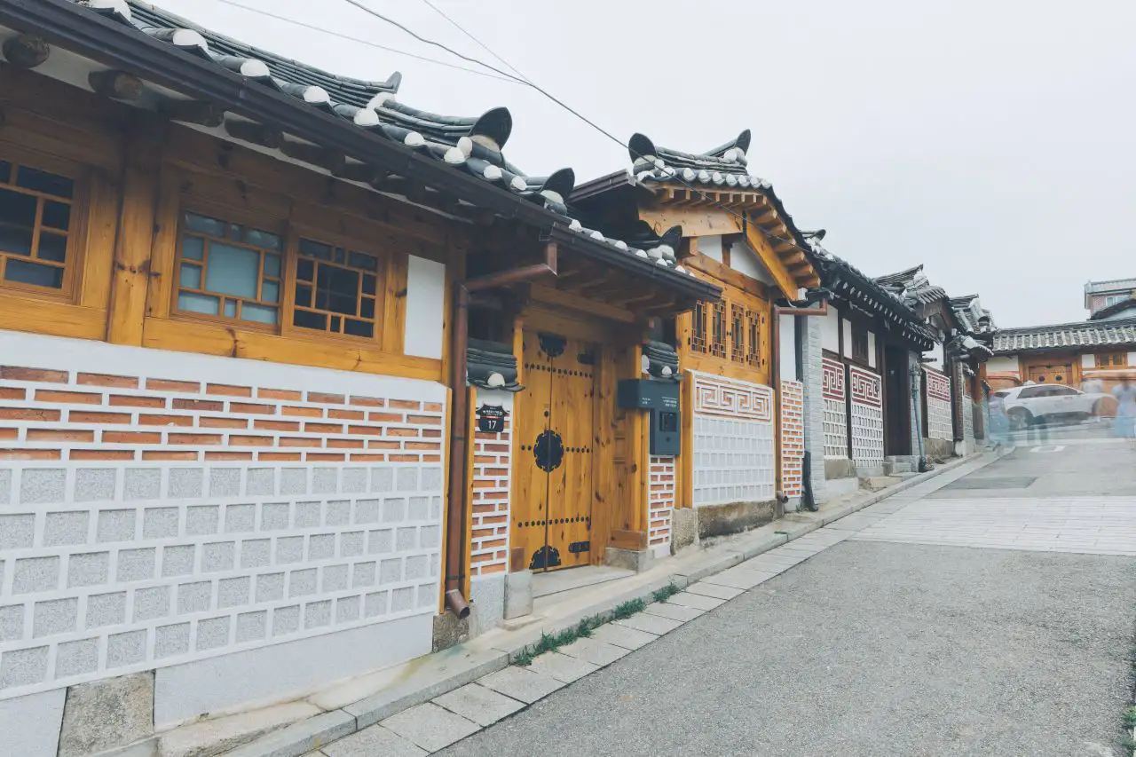A sloping Bukchon lane lined with hanok houses, wooden gates and white walls