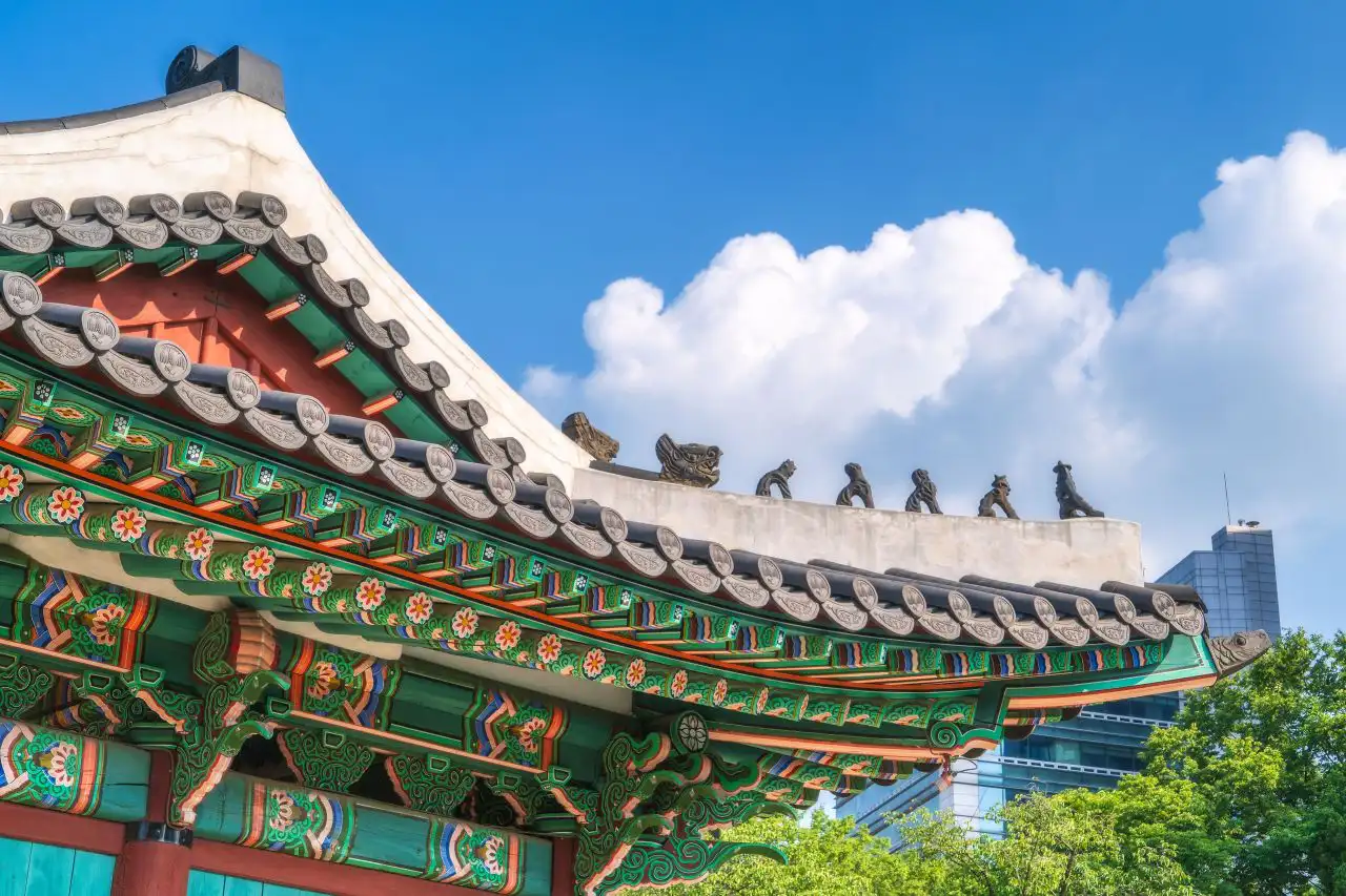 Painted dancheong eaves and the row of guardian figurines on the roof ridge against a blue sky