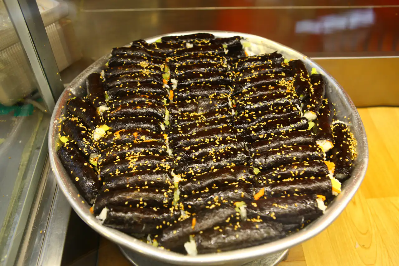 A big bowl of bite-size gimbap rolls sprinkled with sesame