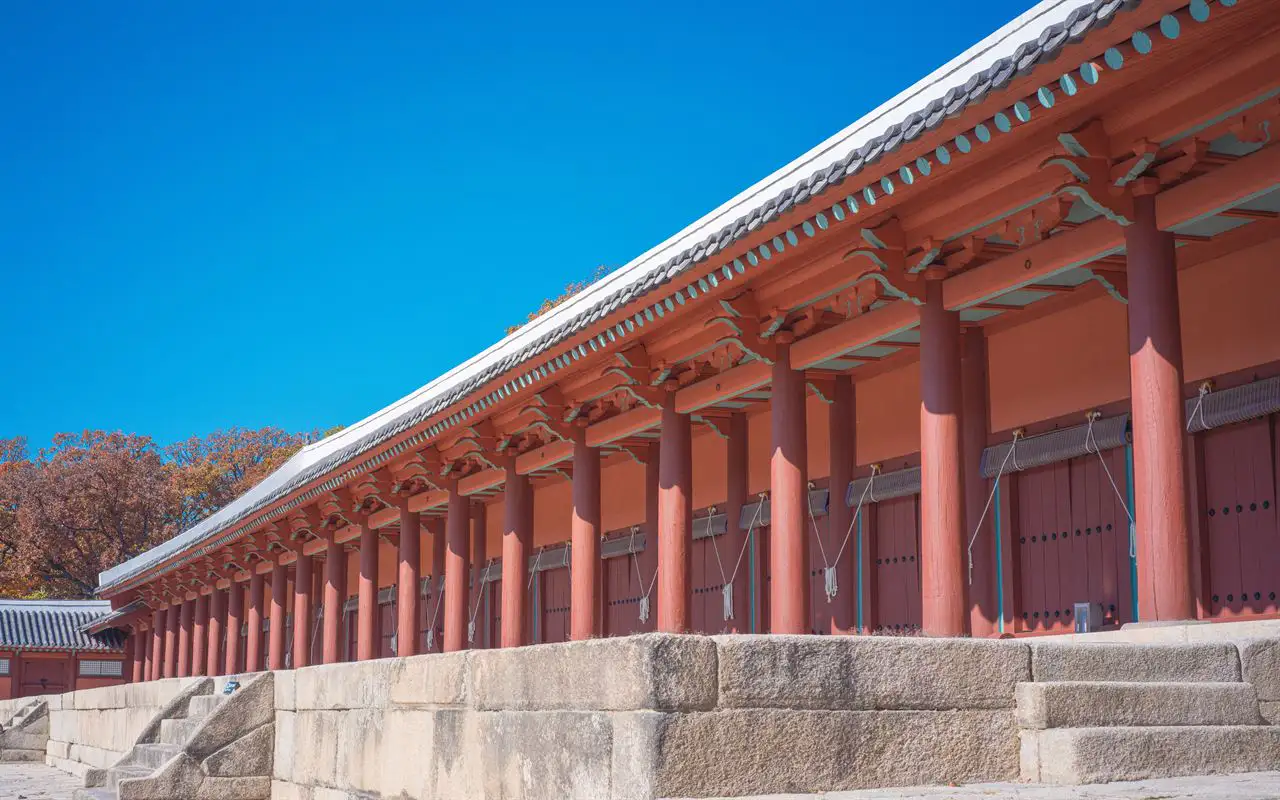 The red columns of Jeongjeon receding in perspective along its high stone platform under a blue sky