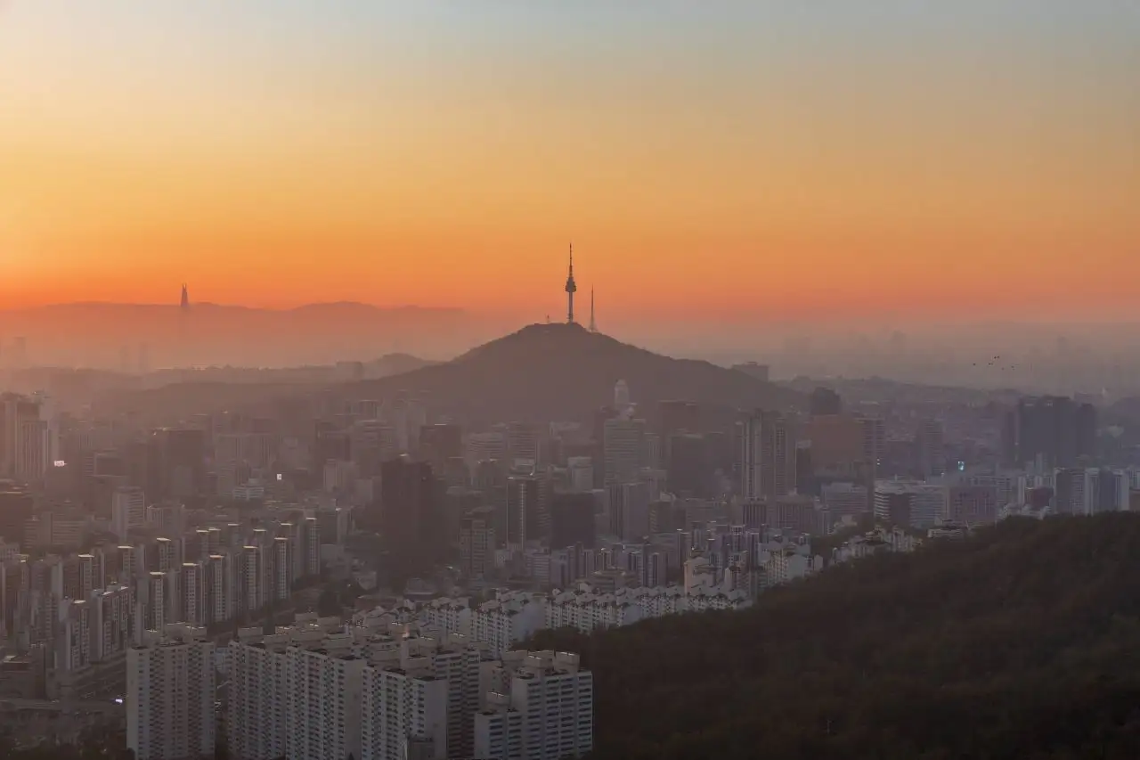 Namsan and N Seoul Tower silhouetted against an orange dawn sky, seen from Ansan
