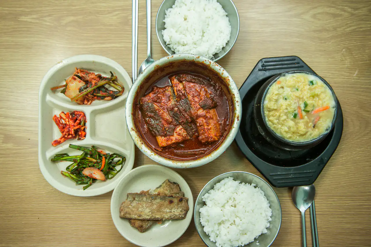 A table of braised hairtail in red sauce with steamed egg, rice and side dishes