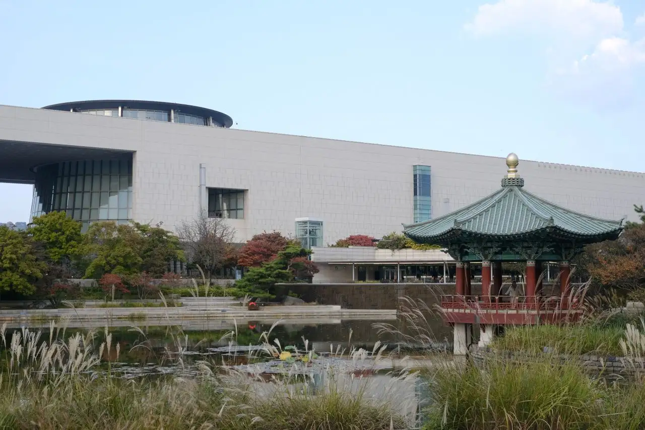 The green-roofed Cheongjajeong pavilion by the pond, with the long pale stone museum building behind